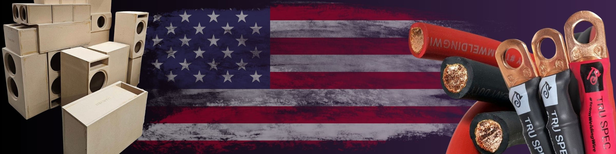 “American flag background with stacked wooden subwoofer enclosure boxes on the left and heavy-gauge power cables with copper ring terminals on the right.”
