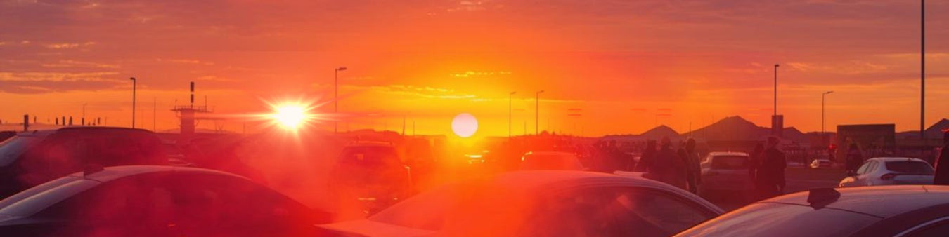 “Bright orange sunset over a crowded parking lot with cars and people silhouetted against the glowing sky.”